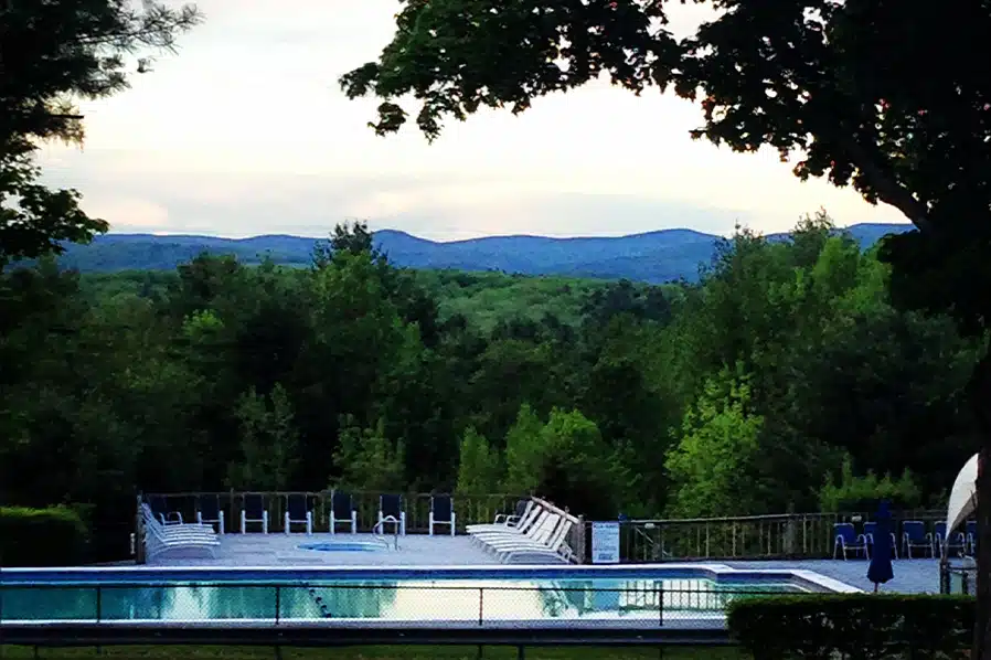 View of pool at Skyway Camping Resort surrounded by trees with mountain range in the background, one of the recent Blue Water Development portfolio additions.